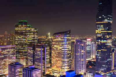 Illuminated buildings in city against sky at night