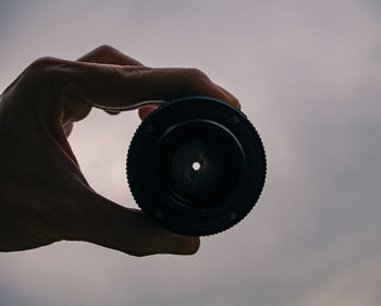 Close-up of man photographing against sky