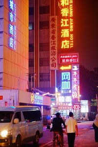 People walking on illuminated road in city at night