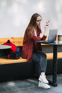 Thoughtful tired college student girl with laptop and books preparing for exams in cafe