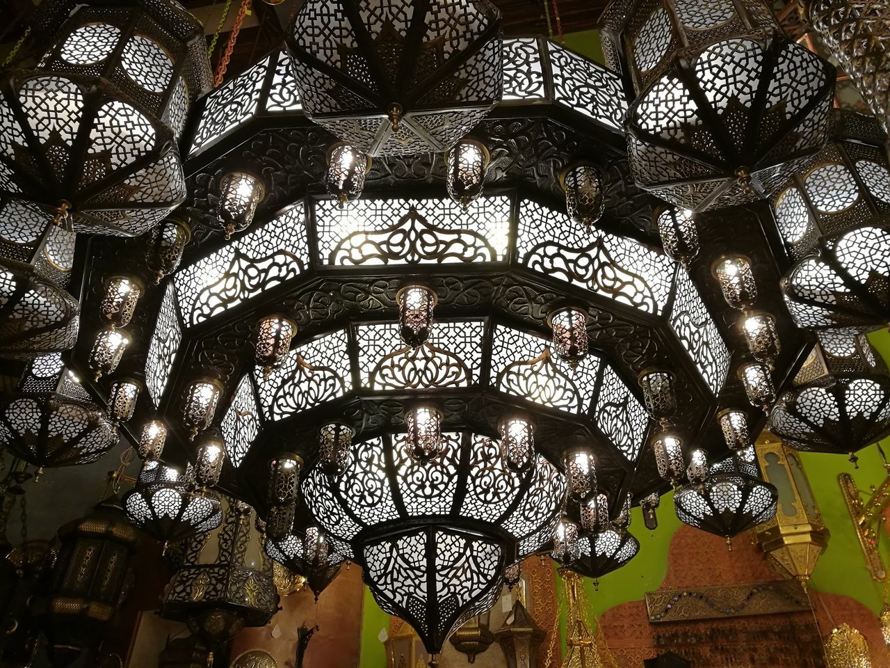 LOW ANGLE VIEW OF ILLUMINATED LIGHTING EQUIPMENT HANGING FROM CEILING