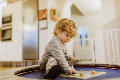 Cute baby girl playing with toy while sitting at home