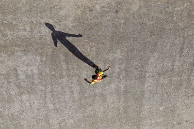 High angle view of man walking on road during sunny day