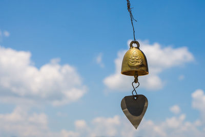 Low angle view of clock hanging against sky