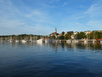 Sailboats in the harbor of flensburg by buildings against sky