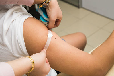 Cropped hand of female doctor applying bandage on patient arm in clinic