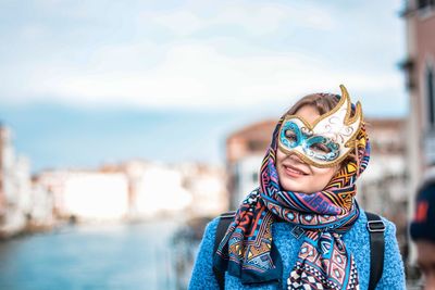 Portrait of young woman wearing sunglasses standing against sky in city