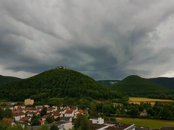 Houses on mountain against storm clouds