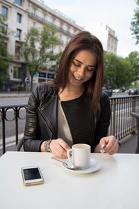 Young woman having coffee while sitting at sidewalk cafe