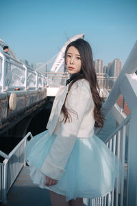 Portrait of smiling young woman standing by railing