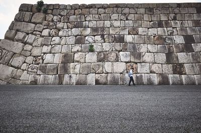 Full length of man standing against brick wall