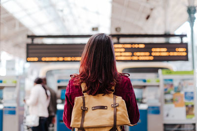 Rear view of woman standing at railroad station