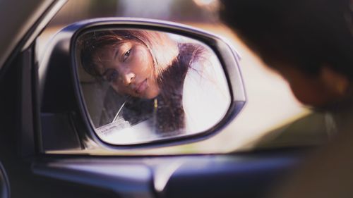 Reflection of woman on side-view mirror