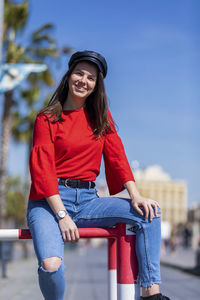 Smiling teenage girl wearing red top in city during sunny day