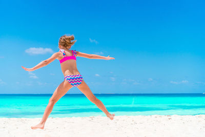 Full length of woman on beach against blue sky