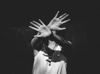 Woman with face covered by hands against black background