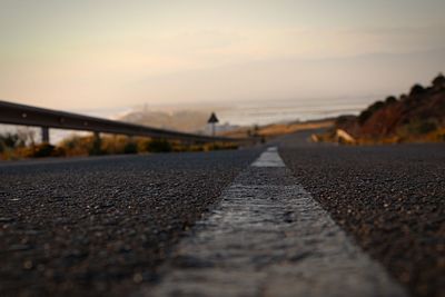 Surface level of road against sky during sunset