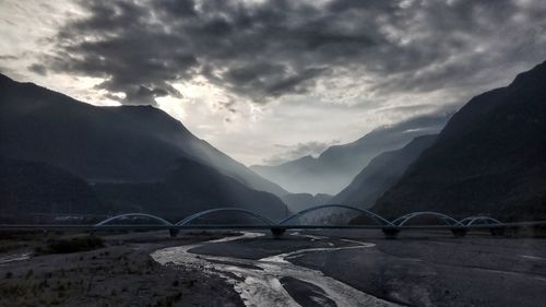 Scenic view of river by mountains against sky