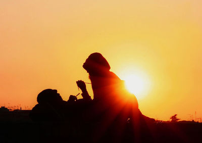 Silhouette couple against orange sky during sunset