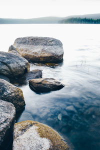 Rocks in lake during foggy weather