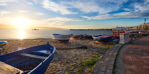 Boats moored on sea against sky during sunset