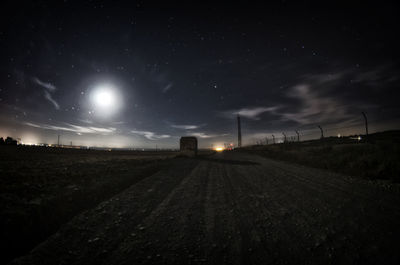 Road amidst field against sky at night