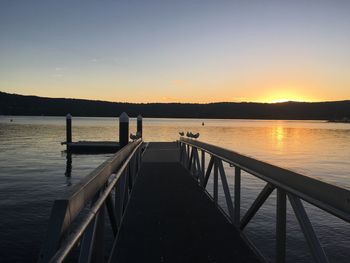 Pier over lake against sky during sunset