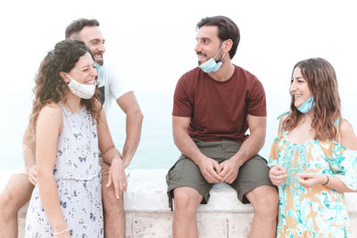 Smiling couple wearing flu mask talking while standing outdoors