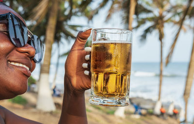African happy woman drinking a beer out at a beach bar in accra ghana