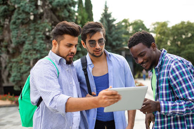 Young man looking at camera while standing on mobile phone