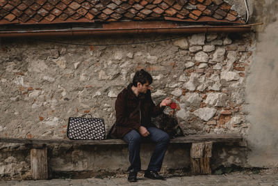 Full length of woman sitting against wall