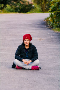 Portrait of young woman sitting on road