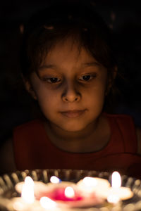Girl looking at lit candle in darkroom