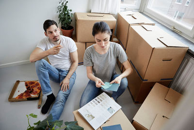 Thoughtful couple with pizza and color swatches during new home relocation