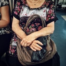 Midsection of woman with hands sitting outdoors