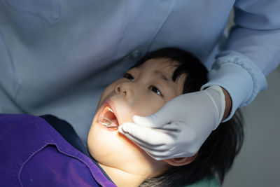 Hand of doctor dentist is working on the teeth of asian little kid patient in dental clinic