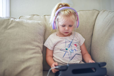 Cute baby girl sitting on sofa at home