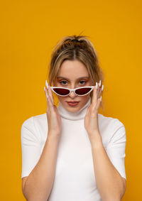 Portrait of a beautiful young woman against yellow background