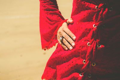 Midsection of woman in red dress with hand on hip