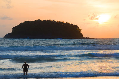 Silhouette person standing on beach against sky during sunset