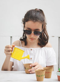 Caucasian teenage girl in a white shirt, sunglasses  holds a yellow watering can