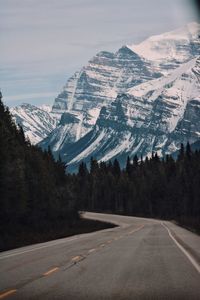 Scenic view of snowcapped mountains and winding road against sky