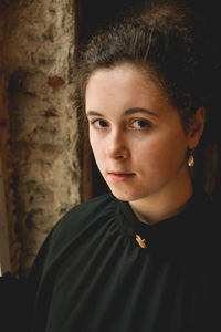 Close-up portrait of young woman standing against wall