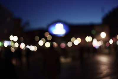 Defocused lights against blue sky at night