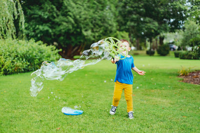 Boy in park playing with large bubbles