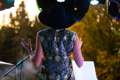 Rear view of woman with hat standing against railing
