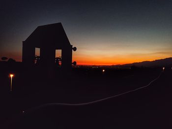 Silhouette built structure against sky at sunset