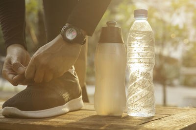 Close-up of man holding glass bottle on table