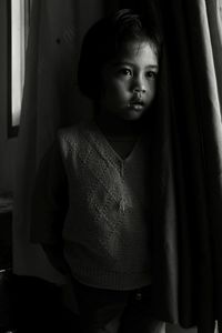 Close-up of girl hiding behind curtain at home