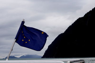 Low angle view of flags over mountain against sky
